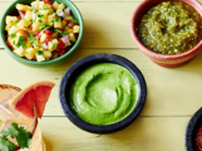 Bowls of salsa, green sauce and guacamole laid out on a table