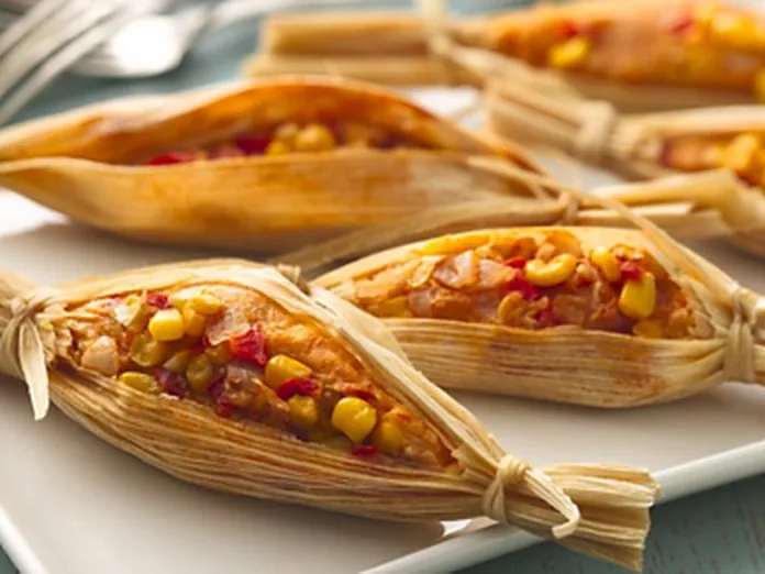 Vegetarian tamales in corn husks filled with corn, peppers and vegetables