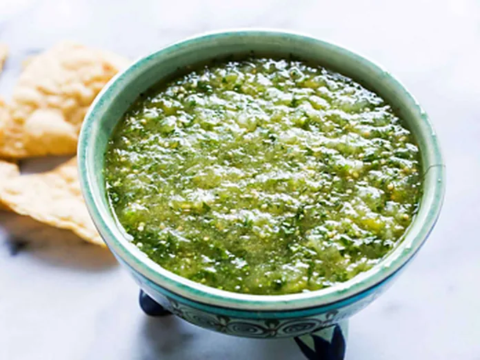 A bowl of bright green tomatillo verde salsa served with tortilla chips